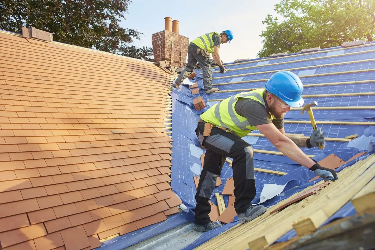 Expert roofers from Trustmark Roofing installing new clay tiles on a pitched roof, demonstrating quality craftsmanship for new roof installations.