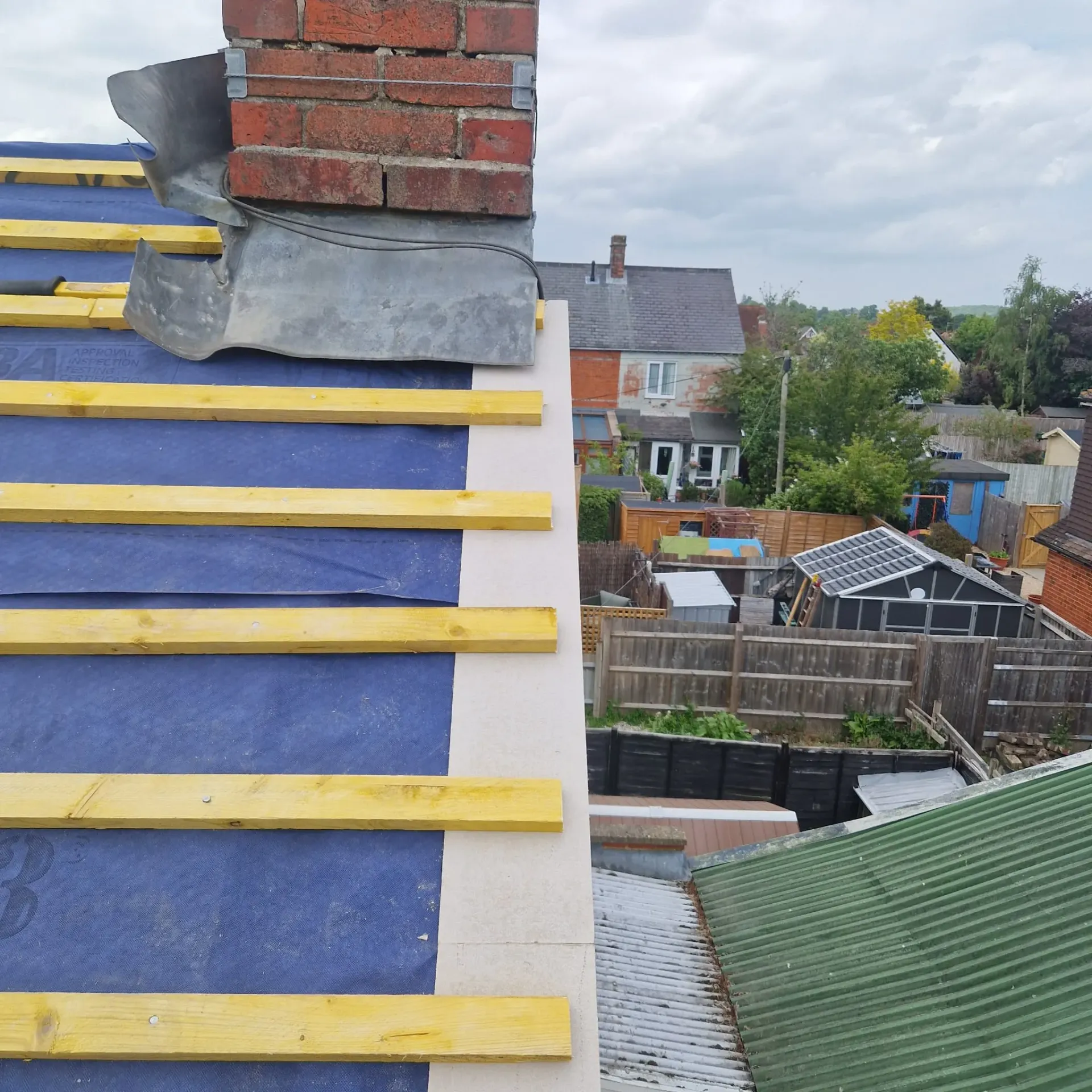 Pitched roof construction with new battens, underlayment, and chimney lead flashing by Trustmark Roofing.