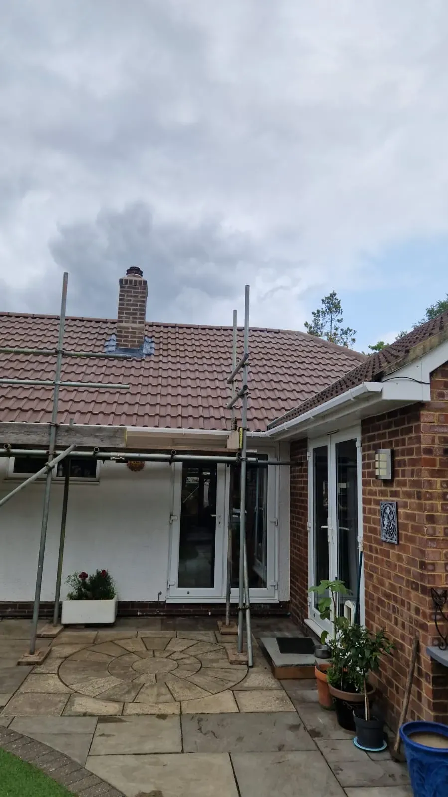New red tiled pitched roof installation with scaffolding on a residential home by Trustmark Roofing.