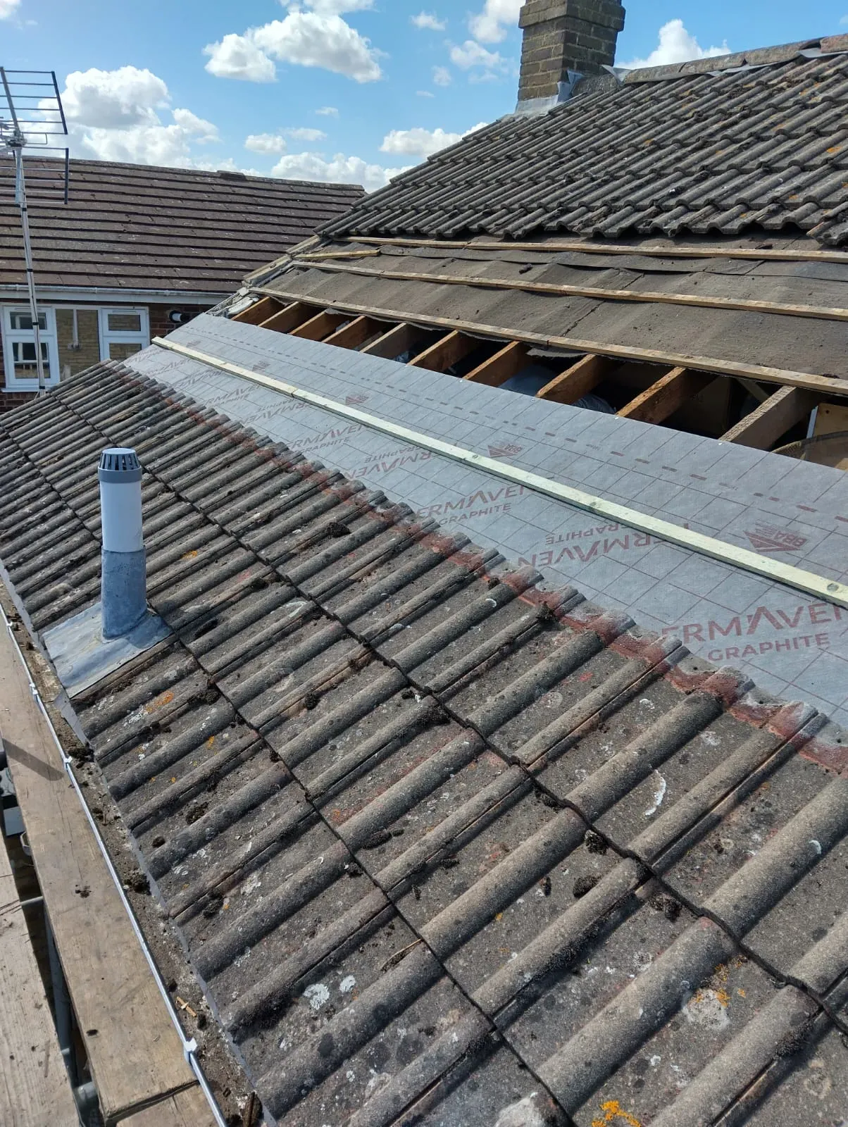 Residential roof being repaired or replaced, showing a mix of weathered tiles and modern roofing underlayment (Thermaven Graphite) with battens.
